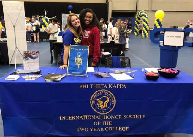 Phi Theta Kappa students behind their table promoting their program at a campus event.