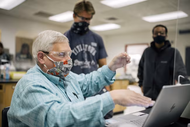Karl Seper holding test tube teaching students.