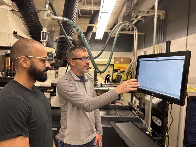 Assistant professor Scott Van Hoven shows a student how to use the latest process monitoring tech in the plastics lab.