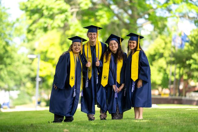 Promise Zone students pose wearing graduation caps and gowns.