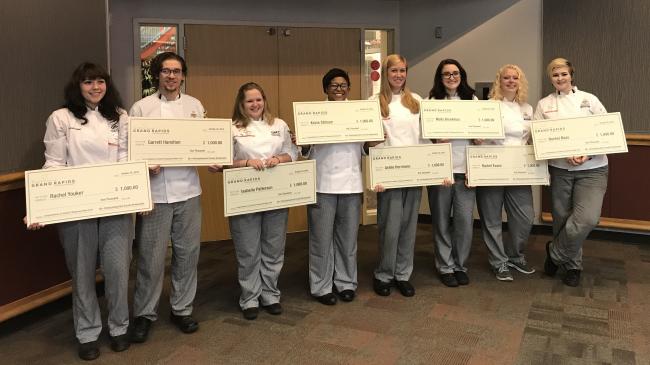 Eight culinary students hold up giant checks in front of the Heritage restaurant.