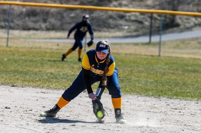 GRCC infielder scooping up a ball in a softball game.