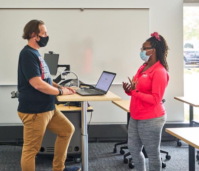 Sean Mackey speaking with a student in a classroom.