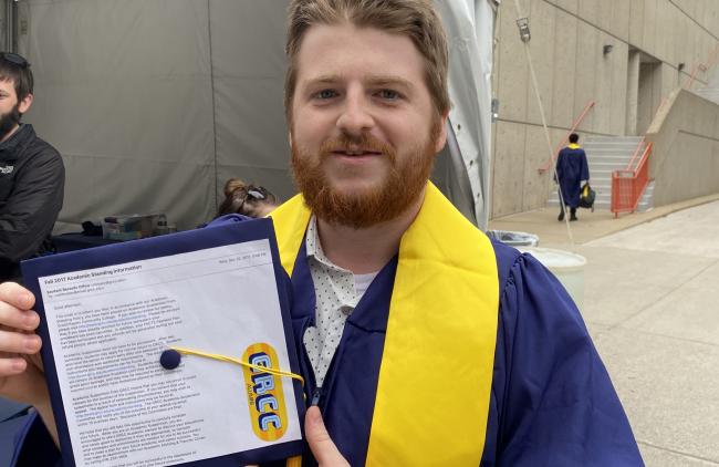 Seth Noyes holding up his cap with his academic suspension letter on it.