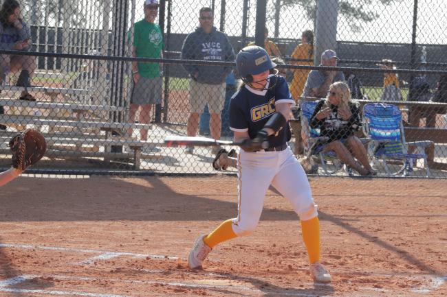 A GRCC softball player swinging at a pitch.
