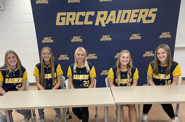 Softball players in their new uniforms after signing with the college.