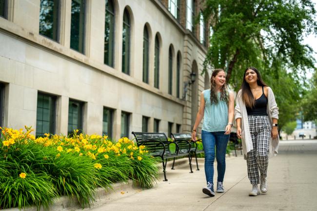 Two guest students walk side by side on GRCC's main campus.