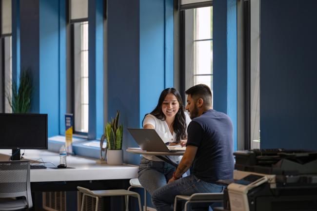 Two students working together on a laptop.