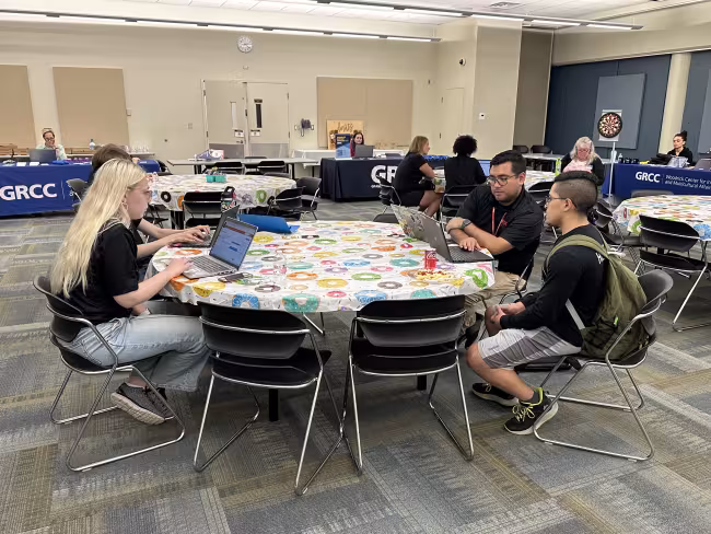 TRIO team members sit at a round table during a resource fair.