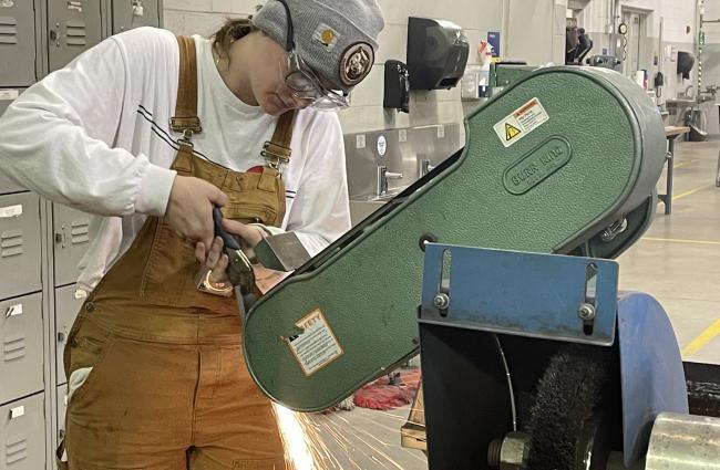 Tarisa Rademacher working with a machine making sparks.