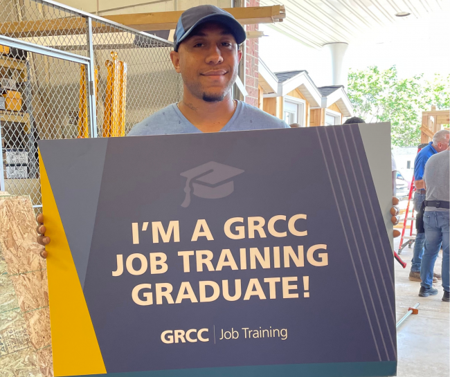 Tevon Bryant holding a sign reading "I'm a GRCC Job Training graduate!"