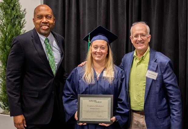 Wrindy Hauser posing with GRCC President Pink and Autocam's John Kennedy at commencement.