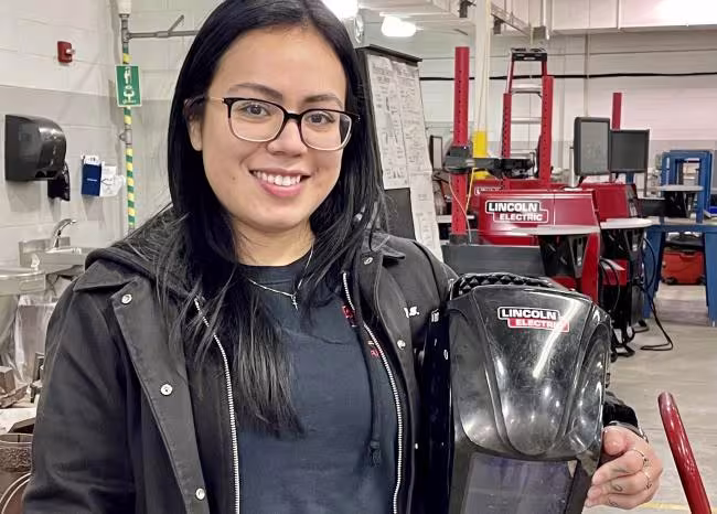 Stephany Borjas holding her welding helmet.