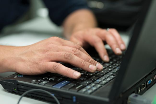 Hands of a student working on a laptop.