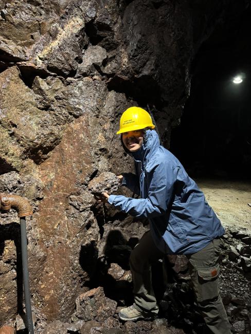 Yasmina Zimmer poses wearing a hardhat near a rock formation.