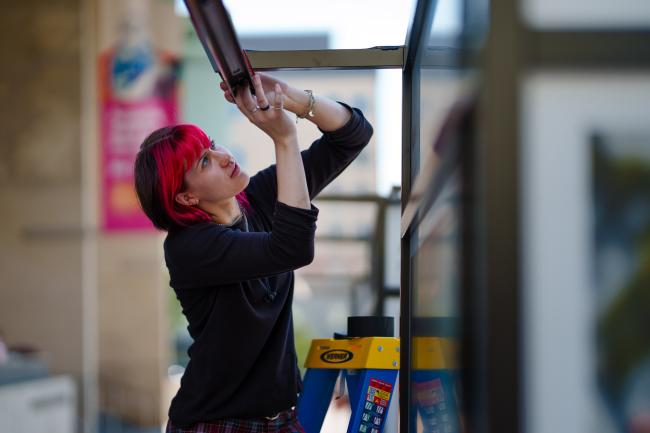 A person concentrates, working with a metal beam.