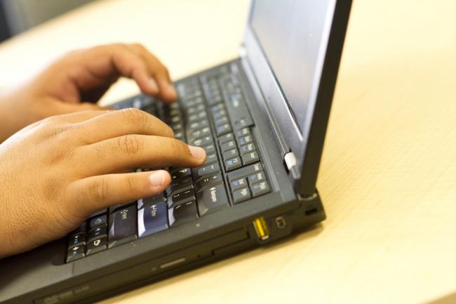 Close-up of a person's hands typing on a laptop.