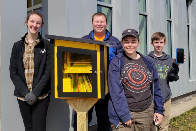 From left, GRCC students Ester Carpenter, John Chappelow, Alycia Pietrzak, Oryan Hammond and Zoe Paskewicz (on phone screen) built and stocked little lending libraries at three Kenowa Hills elementary schools.