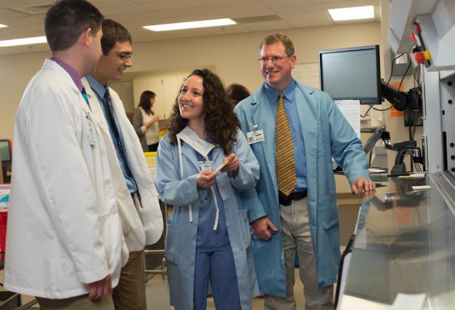 Students and doctors in lab coats working together.