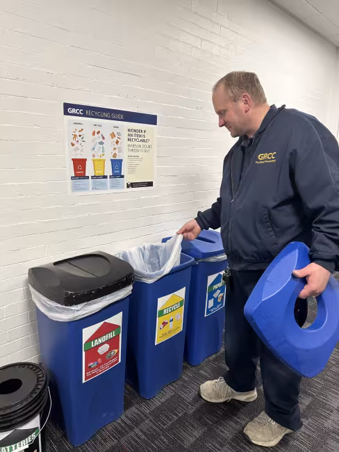 A person removes a bag in a recycling bin.
