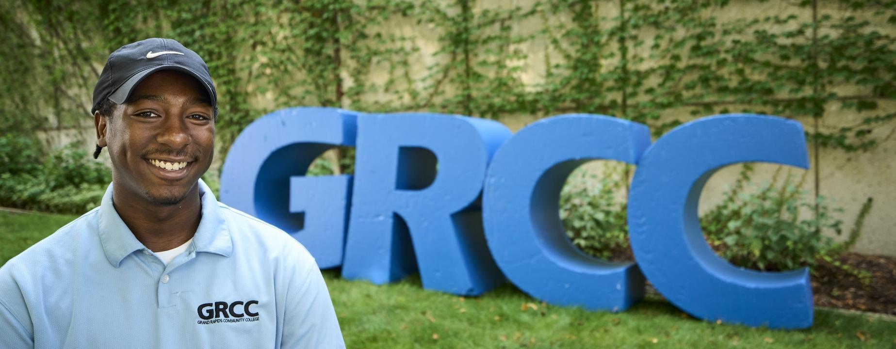 Student standing next to the GRCC letters