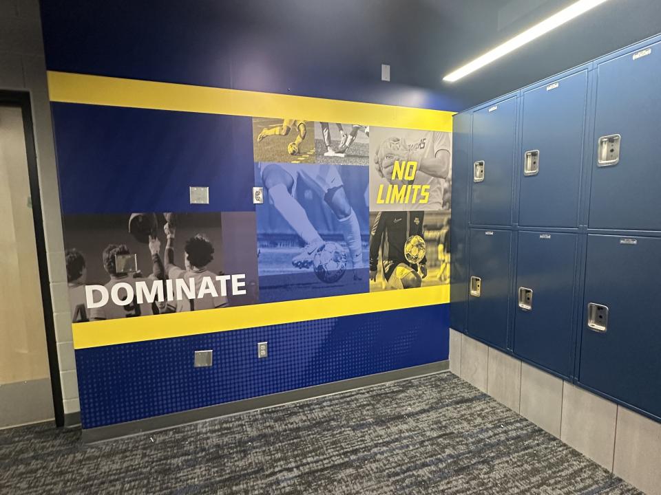 A locker room with GRCC-branded wall art reading "Dominate" and "No Limits."