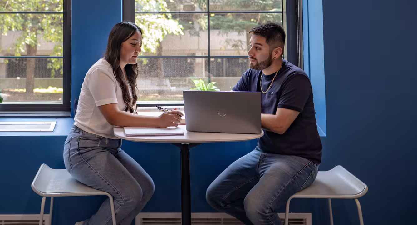 Two students work together on a laptop