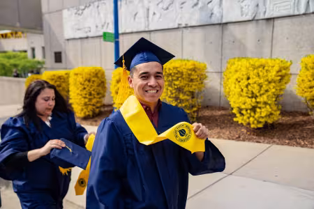 Student in cap and gown showing off his stole