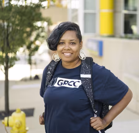 Student smiling and carrying a backpack on campus