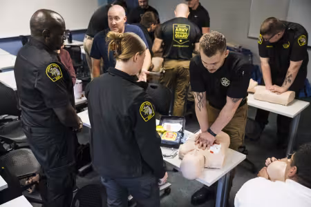 People in uniform practice CPR on dummies. 