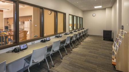 A room with interior windows and chairs facing the windows.