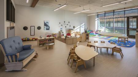 A room with children's tables, windows and toys.