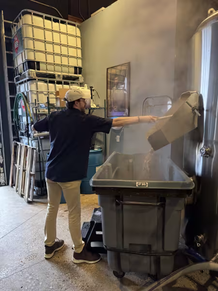 A person works over a steaming bin.