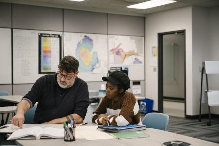 A tutor and a student work at a table.