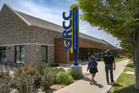 Two people walk past a GRCC sign.