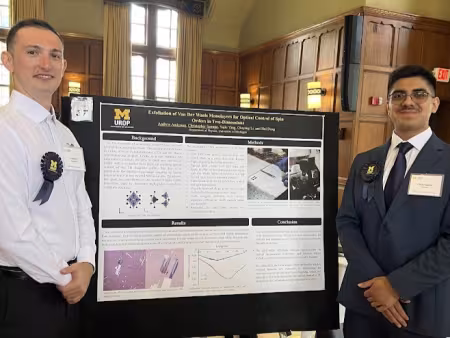 Two people stand in front of an academic research poster.
