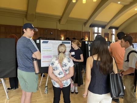 A person presents an academic research poster to a small group.