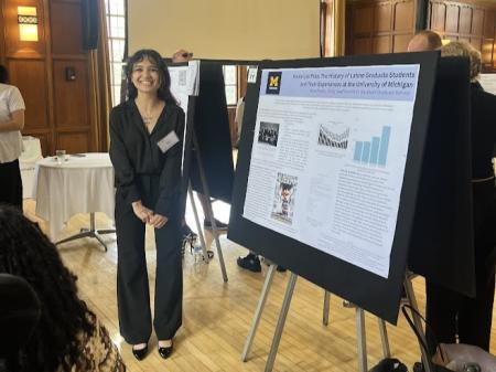 A person stands in front of an academic research poster.