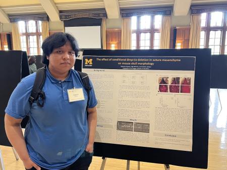 A person stands in front of an academic research poster.