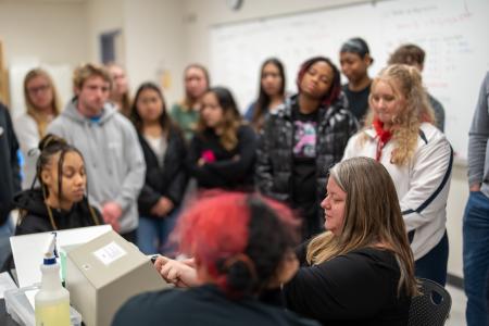A group of biology students gather around Dr. Evans in the classroom.