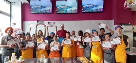Students on a culinary study away trip proudly hold up their certificates in a group photo.