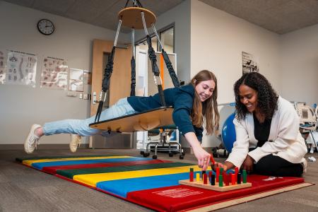 Two students practice using therapy equipment in the lab at GRCC.