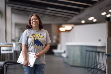 GRCC student wearing a Raiders shirt holds a laptop.