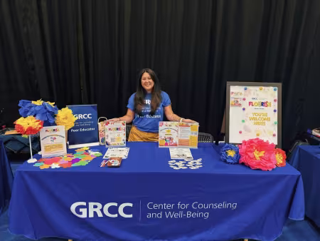 Toni stands behind a resource table for the Center for Counseling and Well-Being