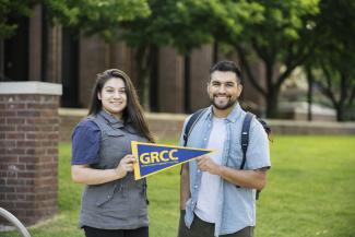 Students smiling and holding a GRCC pennant.