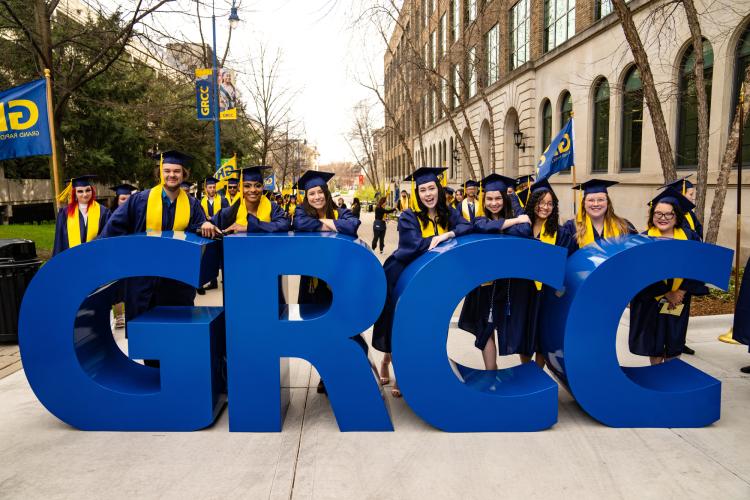 Graduates in front of large letters spelling GRCC.