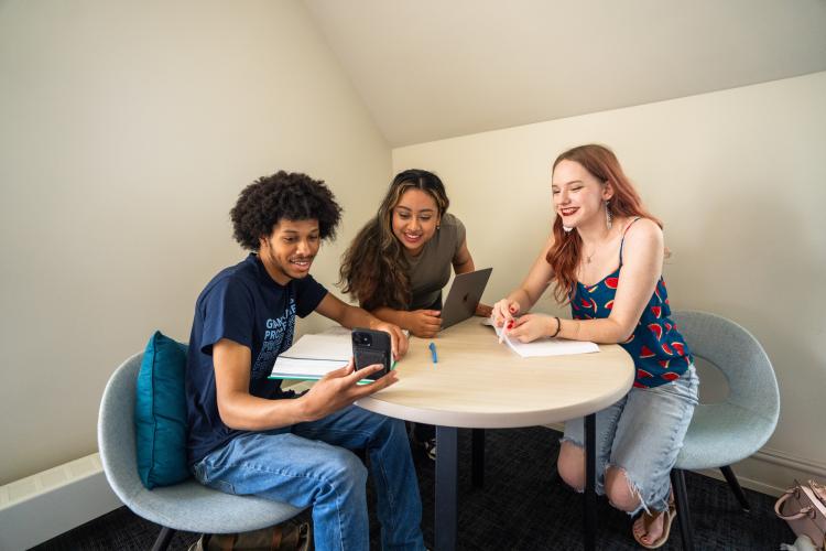students sitting at a table looking at a cellphone