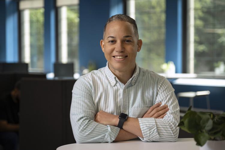 Joel Reyes Hernandez seated with arms folded on GRCC's campus.