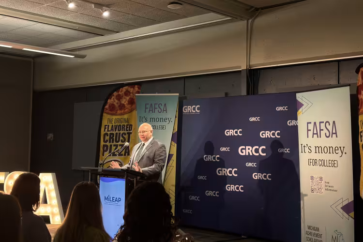 GRCC President Charles W. Lepper stands at a podium in front of a GRCC backdrop.