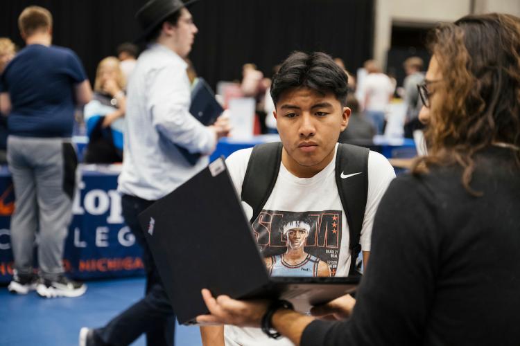 A male student meets with a staff member at a college transfer fair on GRCC's campus.